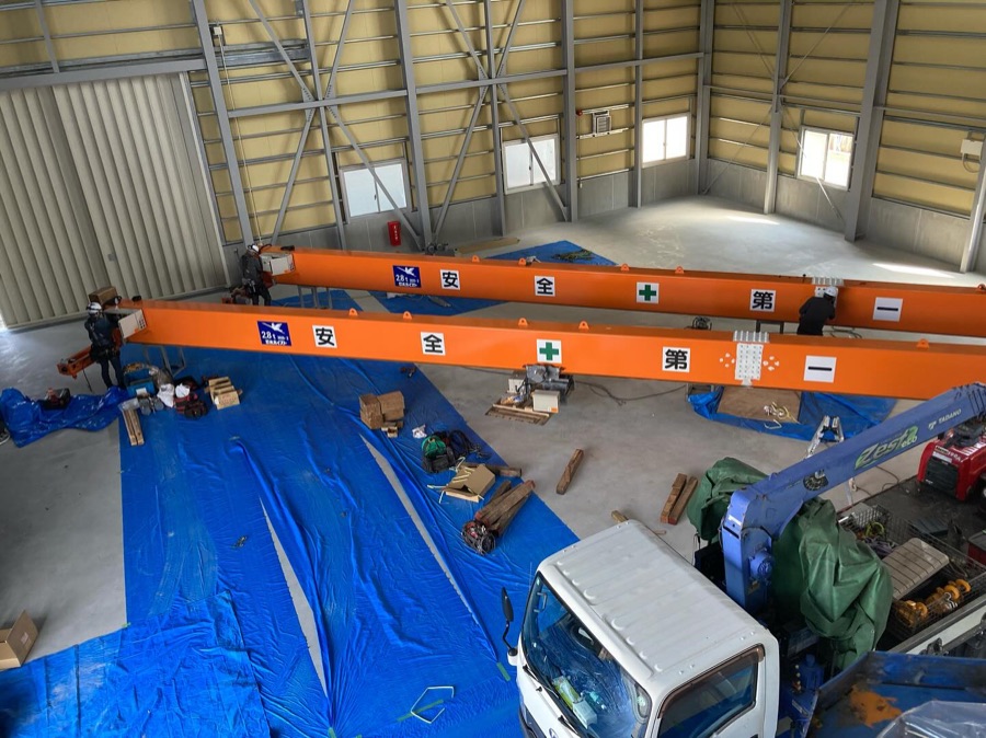 建設中の建物脇に仮置きされたオレンジ色のクレーン梁とホイスト